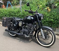 a black motorcycle parked on the side of a road in front of bushes and trees