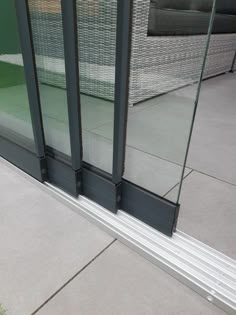 an open glass door on the side of a building with grass in front of it