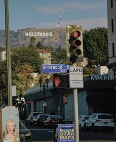 a traffic light sitting on the side of a road next to a sign that says hollywood