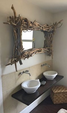 a bathroom with two sinks and a mirror made out of driftwood branches on the wall