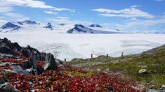 people standing on top of a snow covered mountain with mountains in the backgroud