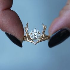 a close up of a person's hand holding a ring with a diamond in it