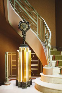 a clock sitting on top of a table next to a stair case