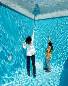 two people are standing in an underwater pool