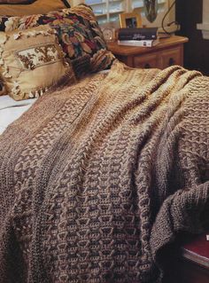 a bed covered in a brown blanket and pillows