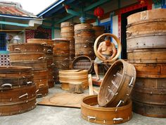 a man is sitting in front of many wooden barrels