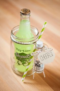 a glass bottle with a green and white striped straw in it sitting on a wooden table