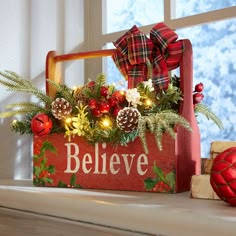 a wooden box filled with pine cones and christmas decorations sitting on top of a window sill