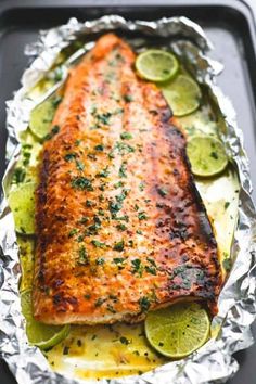 a piece of salmon on foil with limes and cucumbers