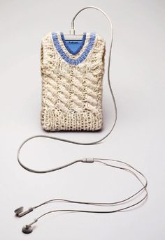 a white sweater with blue trim is hooked up to a charger and earbuds