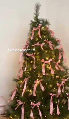 a small christmas tree with pink bows on it