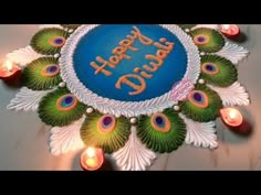 a birthday cake with peacock feathers and candles around it that says happy diwali