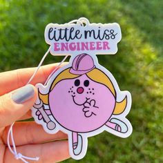 a hand holding a pink sticker with the words little miss engineer written on it