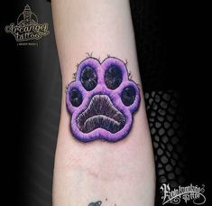 a purple dog paw tattoo on the left arm