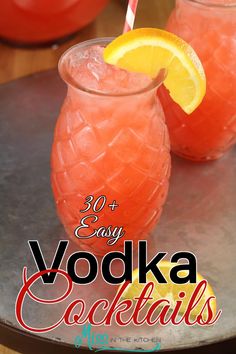 two glasses filled with vodka cocktails on top of a metal tray next to lemon wedges