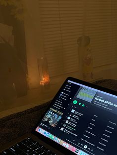 an open laptop computer sitting on top of a table next to a vase with flowers