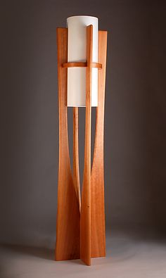 a tall wooden lamp with a white shade on it's top and bottom part