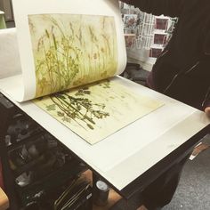 a person standing next to a large roll of paper on top of a printer table