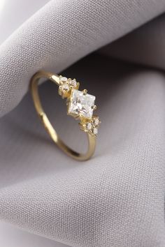 a gold ring with three stones on it sitting on top of a white cloth next to a