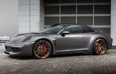 a silver sports car parked in front of a garage door with gold rims on it