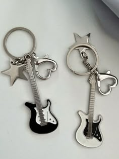 two metal key chains with guitars and stars on them, one is black and the other is silver