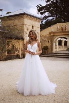 a woman standing in front of a building wearing a wedding dress