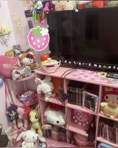 there is a television and many toys on the shelf in this room with pink walls