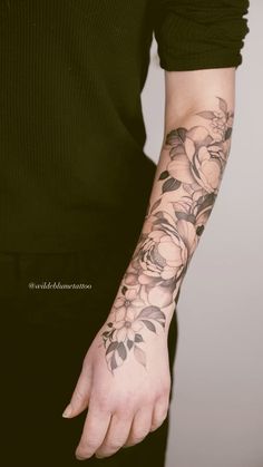 a woman's arm with flowers on it and her hand in the air,