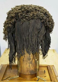 the wig is made from dreadlocks on top of a wooden stand