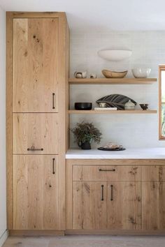 a kitchen with wooden cabinets and white counter tops, along with shelves filled with dishes