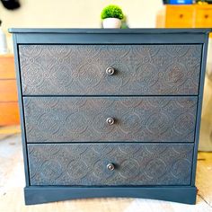 a blue dresser with two drawers and a potted plant in the top one drawer