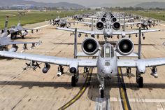 a row of fighter jets sitting on top of an airport tarmac