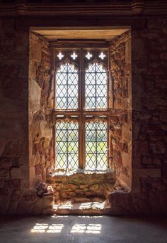 an old stone building with a stained glass window in the center and sunlight streaming through it