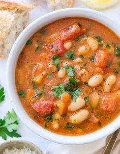 a white bowl filled with soup next to bread and parsley