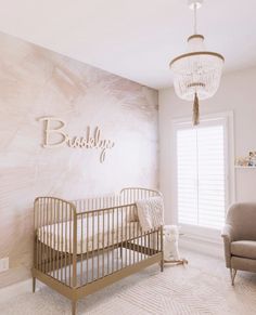 a baby's room with a crib, chair and chandelier