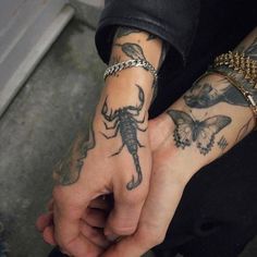 a man with tattoos on his arm and wrist holding onto another person's hand