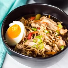 a black bowl filled with noodles and an egg