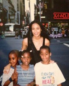 a woman posing for a photo with her four children in front of a city street