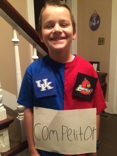 a young boy holding a sign that says com petition