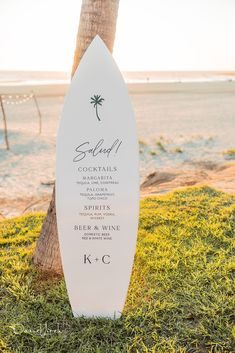 a surfboard is sitting in the grass next to a palm tree on the beach