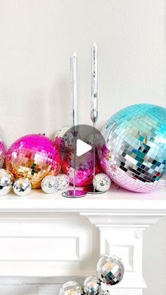 disco balls and candles sit on a mantle in front of a mirror ball fireplace mantel