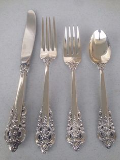 an assortment of silverware including forks, knives and spoons on a gray surface