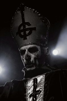 a black and white photo of a man wearing a priest's outfit in the dark