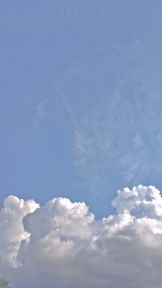 an airplane is flying high in the sky with clouds behind it and blue skies above