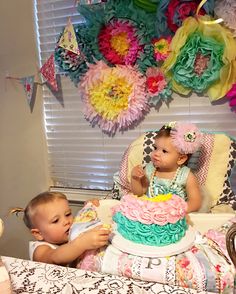 two babies sitting in front of a birthday cake