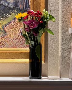 a vase filled with flowers sitting on top of a window sill next to a painting