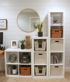 a white bookcase with baskets on it and a mirror above the bookshelf