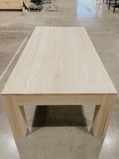 a wooden table sitting on top of a cement floor in a room filled with furniture