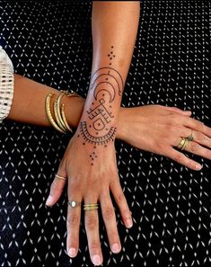 two women's hands with tattoos and rings on their wrists, both holding each other