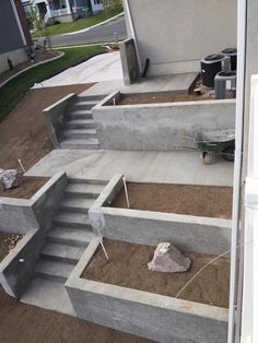 concrete steps leading up to a house in the middle of a yard with dirt on the ground